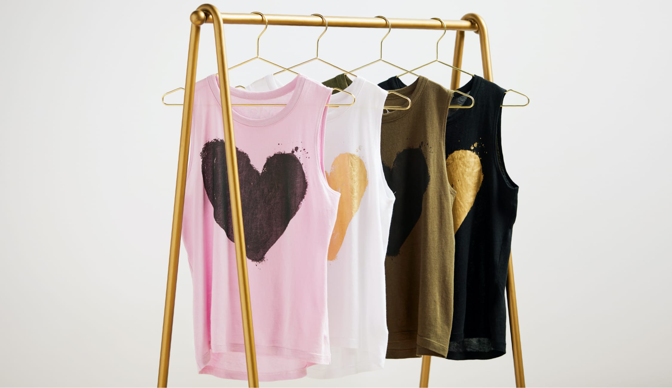 tank tops with heart graphic hanging from a rack