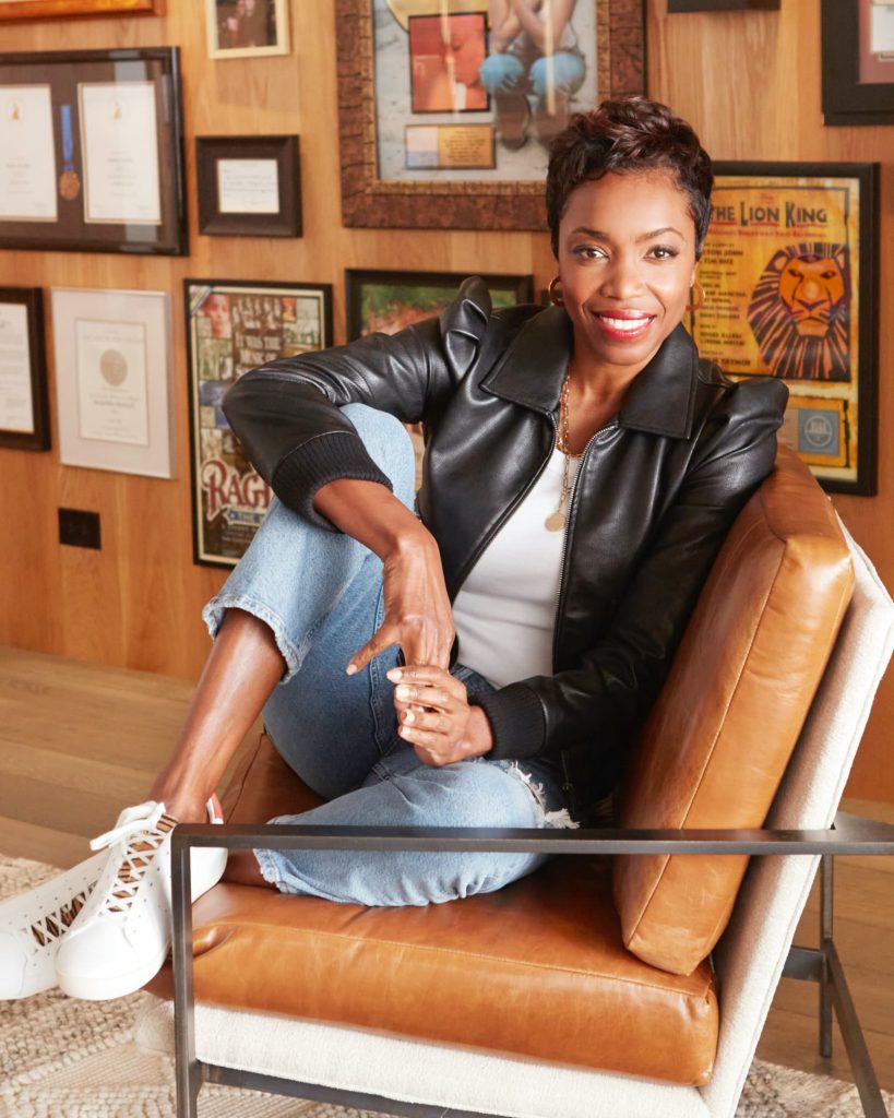 Heather Headley sitting in an arm chair and smiling